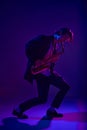 Talented jazz man, virtuoso playing saxophone in vibrant pink neon light against dark studio background.