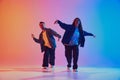 Talented male and female hip-hop dancers performing in synchronously moves against gradient studio background in neon Royalty Free Stock Photo