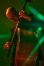 Talented musician playing jazz on double bass in red-green neon, stage light against gradient studio background. Royalty Free Stock Photo