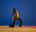 Talented. Portrait of young girl dancing heels dance in stylish clothes over blue background in neon with mixed lights Royalty Free Stock Photo