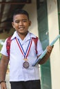 A talented and smart school boy outside a simple rural classroom. Holding textbooks and wearing an honor medal Royalty Free Stock Photo