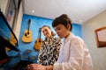 Talented teenager boy musician having a piano lesson with his teacher. Female pianist explaining the correct position of Royalty Free Stock Photo