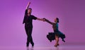 Talented young man and woman, professional dancers performing tango over purple background on neon lights. Concept of Royalty Free Stock Photo