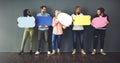 Talk it out. Studio shot of a diverse group of people holding up speech bubbles against a gray background. Royalty Free Stock Photo