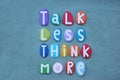 Talk less, think more, creative slogan composed with multi colored stone letters over green sand Royalty Free Stock Photo