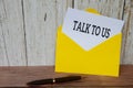 Talk to us text on white notepad in yellow envelope. Customer service concept Royalty Free Stock Photo