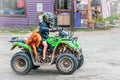 Talkeetna Alaska USA - Child in helmet drdivng green four wheeler with dog draped across back of seat in the funky