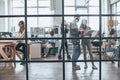 Talking business details. Full length of young modern people working and communicating together while standing behind the glass w Royalty Free Stock Photo