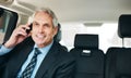 Talking business on the way to work. a mature businessman using a mobile phone in the back seat of a car. Royalty Free Stock Photo