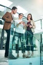 Talking digital strategy. a group of colleagues talking together over a digital tablet while standing in a large modern