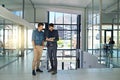 Talking digital strategy. two colleagues talking together over a digital tablet while standing in a modern office.