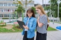 Talking teacher and teenage schoolgirl outdoor, school building background Royalty Free Stock Photo