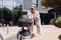 Talking and having fun. Two female friends having a walk with baby carriage outdoors Royalty Free Stock Photo