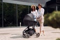 Talking and having fun. Two female friends having a walk with baby carriage outdoors Royalty Free Stock Photo