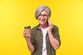 Talking on the phone mature grey haired woman drinking coffee in paper disposable cup. Senior woman laughing holding Royalty Free Stock Photo