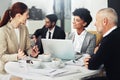 Talking strategy with the team. a group of businesspeople working on a laptop together while sitting at a table in an Royalty Free Stock Photo