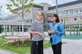Talking teacher and teenage schoolgirl outdoor, school building background Royalty Free Stock Photo