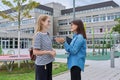 Talking teacher and teenage schoolgirl outdoor, school building background Royalty Free Stock Photo