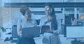 Talking two women in smart casual pointing and tapping tablet in modern office, with laptop Royalty Free Stock Photo