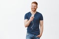 Talking via earphones more comfortable. Portrait of happy attractive masculine redhead male model in blue t-shirt Royalty Free Stock Photo