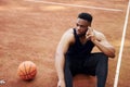 Talks by phone. African american man plays basketball on the court outdoors