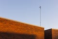 Tall Antenna on Brick Wall Against Clear Blue Sky