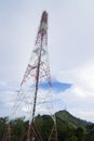 The tall antenna with the mountain and the sky.