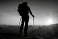 Tall backpacker with poles in hand. Sunny hike day in rocky mountains. Hiker with big backpack stand on rocky view point above Royalty Free Stock Photo