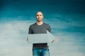 A tall bald man in a gray T-shirt and blue jeans holds in his hands a pointer in the form of an arrow pointing to the side Royalty Free Stock Photo