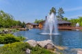 A tall beautiful beating fountain in the middle of a blue lake against a background of wooden buildings with decorative Royalty Free Stock Photo