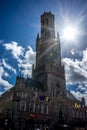 The tall belfry tower with a bright sun solar flare at Brugge, B