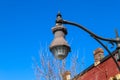 A tall black curved light post near a red brick building with a blue sky background in Douglasville