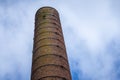 A tall brick chimney stack stretching up to a blue sky full of white clouds.Defunct industrial brick chimney against bright blue Royalty Free Stock Photo