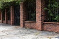 Tall brick and wrought iron wall beside a slate stone walkway, old architectural details, copy space