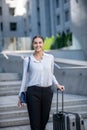 Tall brunette smiling woman walking and carrying a suitcase