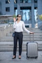 Tall brunette woman standing near her big suitcase and waving her hand Royalty Free Stock Photo