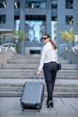 Tall brunette woman in sunglassescarrying her big suitcase