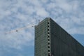 Tall building under construction completely covered with green construction mesh, construction crane, background Royalty Free Stock Photo