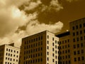 Tall Buildings Against A Cloudy Sky In Sepia