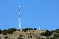 Tall cell phone antenna tower next to small building situated on top of the hill with white cross Royalty Free Stock Photo