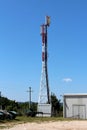 Tall cell phone red and white antenna tower with multiple antennas on top with clear blue sky in background