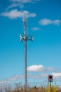 Tall cellular communication tower with multiple antennas rising above trees under bright blue sky Royalty Free Stock Photo