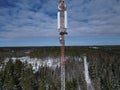 Tall cellular phone tower stands in sharp contrast against a wintery backdrop of a snowy forest. Royalty Free Stock Photo