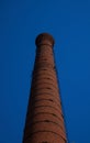 tall chimney old red bricks in an old factory. smoke stack An old brick chimney against a blue sky Royalty Free Stock Photo