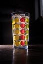 Tall colourfull glass filled with iced lemonade isolated on dark background Royalty Free Stock Photo