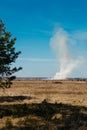 A tall column of white smoke in a dry field in spring. Royalty Free Stock Photo