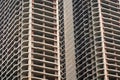 Tall concrete structures rise in an urban setting, showcasing incomplete frameworks and open spaces. Workers are active