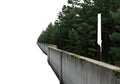 Tall concrete wall surrounded by lush green pine trees in a serene forest setting Royalty Free Stock Photo