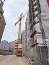 Tall construction crane beside unfinished apartment block. The building is surrounded by scaffolding, with construction materials Royalty Free Stock Photo