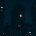A tall, dark building stands against a night sky, with a few lit windows punctuating the Royalty Free Stock Photo